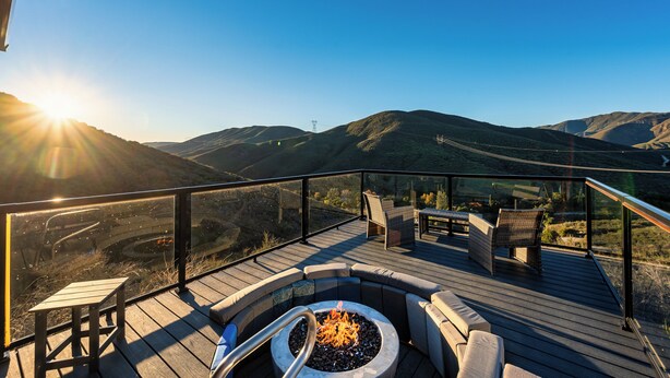 A deck with a fire pit, seating, and a scenic mountain view.