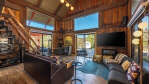 A spacious living area with a large sofa, a television, and a dining area with a table and chairs.