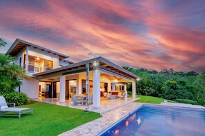 A modern two-story house with an outdoor patio, a swimming pool, and lush greenery. - Casa Hacienda Jaguar (Ojochal)