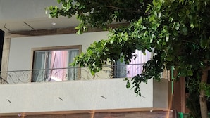 Ein zweistöckiges Gebäude mit Balkon, Baum und einem Vorgeländer.