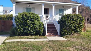 A single-story house with a front porch, a chimney, and a small attached garage. - COMPLETELY REMODELED-- LESS THAN A BLOCK FROM BEACH--
HOT TUB-- NOON CHECK OUT!! (BAY ST LOUIS)