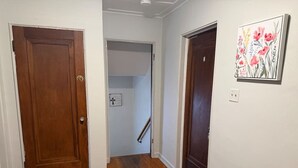 A hallway with wooden doors, a white wall, and a small rug on the floor. - Large Group Stay Near Syracuse University & Dome (Syracuse)