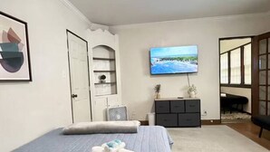 A bedroom with a bed, a TV, a dresser, and a door. - Large Group Stay Near Syracuse University & Dome (Syracuse)