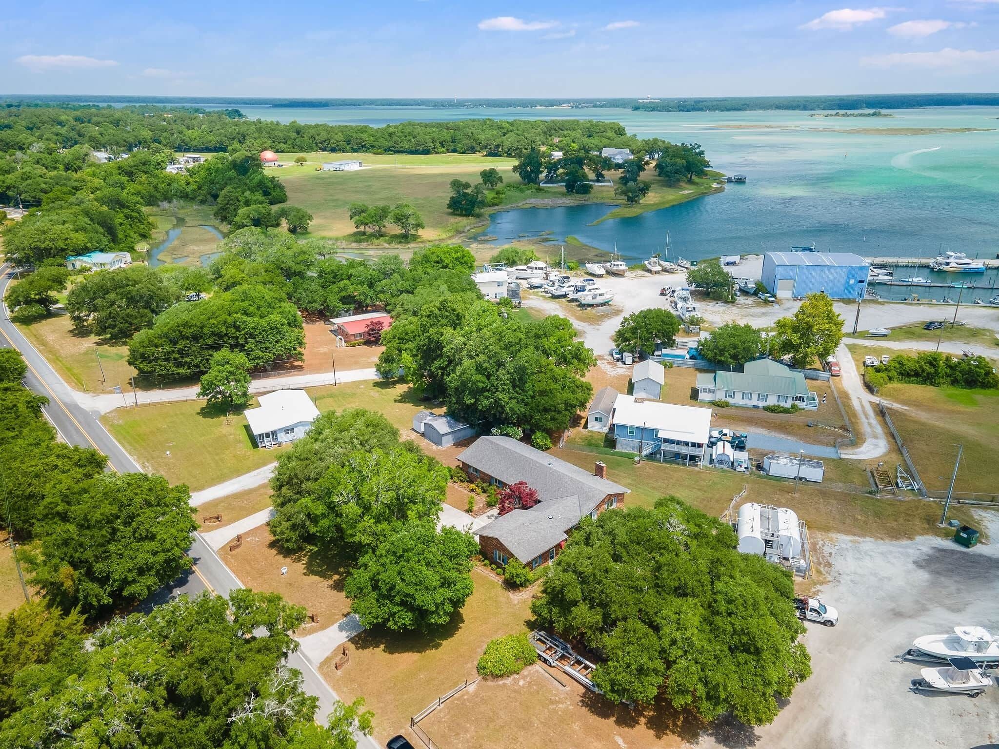 An aerial view of a coastal area with residential buildings, a marina, and a large body of water.