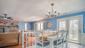 A dining area with a white table and chairs, a chandelier, and a stone wall with a sign.