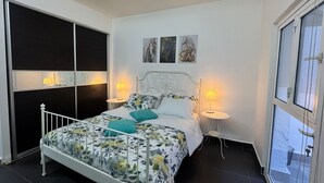 Ein Schlafzimmer mit einem Bett, zwei Nachttischen, einem Fenster und einer Tür.