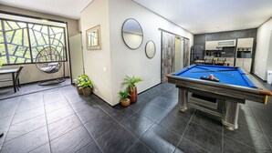 Ein modernes Wohnzimmer mit Billardtisch, Essbereich und Küche.