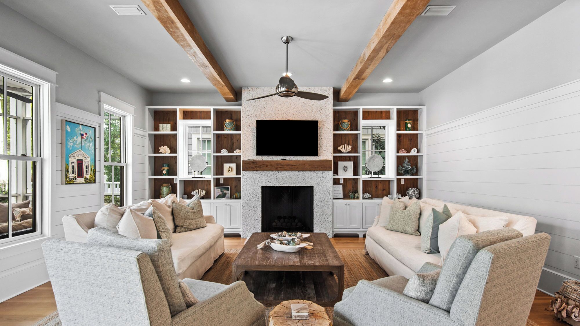 A spacious living room with a fireplace, built-in shelving, and a large flat-screen TV.
