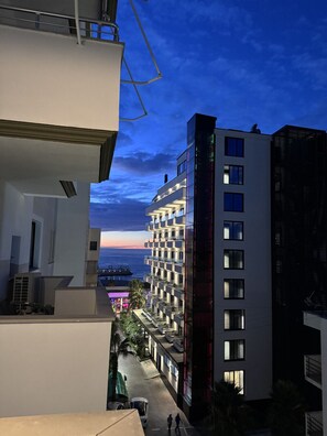 A multi-story building with balconies, a view of the sea, and a clear sky.
