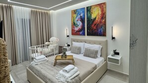 Ein modernes Schlafzimmer mit einem großen Bett, Nachttischen, einem Babybett und abstrakter Wandkunst.