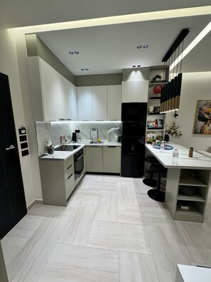 Una cocina moderna con una isla central, electrodomésticos integrados y un comedor con taburetes de bar.