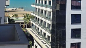 Ein mehrstöckiges Gebäude mit Balkonen, Blick auf den Strand und blauem Himmel.