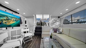 Ein modernes Wohnzimmer mit einem großen Flachbildfernseher, einer Couch, einem Couchtisch und einer Treppe, die zu einer oberen Ebene führt.
