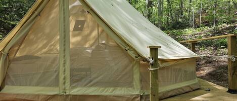 A tent set up on a wooden deck in a forest.