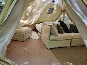 A tent with a bed, a sofa, and a small table.