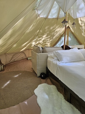 A tent with a bed, pillows, a rug, and a lantern. - Whisper "Hollar" | Secluded Luxe Glamping Retreat (Turtletown)