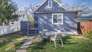 A small house with a covered patio, a fenced yard, and a wooden deck.