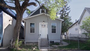 A single-story house with a white door, a small porch, and a fenced yard.
