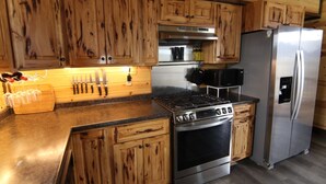 A kitchen with wooden cabinets, a stainless steel stove, a refrigerator, and a microwave.