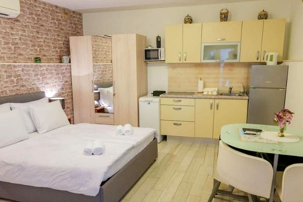Ein Schlafzimmer mit Bett, einer kleinen Küchenzeile und einem Essbereich mit Tisch und Stühlen.