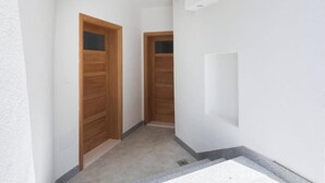 Un couloir étroit avec des portes en bois et un mur blanc.