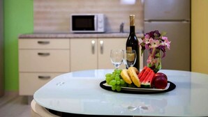 Une table avec une bouteille de vin, deux verres, une assiette de raisins, une banane, des tranches de pastèque et un arrangement floral décoratif.