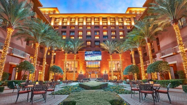 A hotel with a central courtyard, palm trees, and outdoor seating areas.