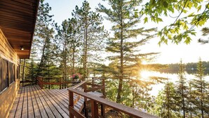 Una terraza de madera con barandilla que da a un lago rodeado de árboles.