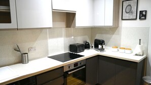 A compact kitchen with a dishwasher, oven, and a coffee maker on the countertop. - Super Central 2 Bedroom Apartment Sleeps 5, 85` TV (Canterbury)