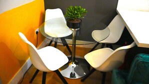 A small, modern room with a glass table, white chairs, and a potted plant. - Super Central 2 Bedroom Apartment Sleeps 5, 85` TV (Canterbury)