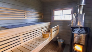 Un sauna con bancos de madera, una ventana y un estufa de leña.