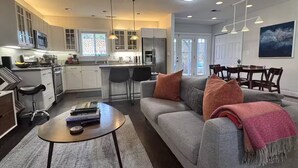 A modern kitchen with white cabinets, a dining area with a table and chairs, and a living room with a sofa and a coffee table. - Soak, Sip, and Stay. Sonoma Retreat Near the Plaza (Sonoma)