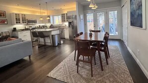 A modern kitchen with a dining area, wooden flooring, and pendant lighting. - Soak, Sip, and Stay. Sonoma Retreat Near the Plaza (Sonoma)