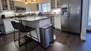 A modern kitchen with a central island, stainless steel appliances, and bar stools. - Soak, Sip, and Stay. Sonoma Retreat Near the Plaza (Sonoma)