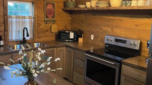 A wooden kitchen with a built-in oven, microwave, and stainless steel sink.
