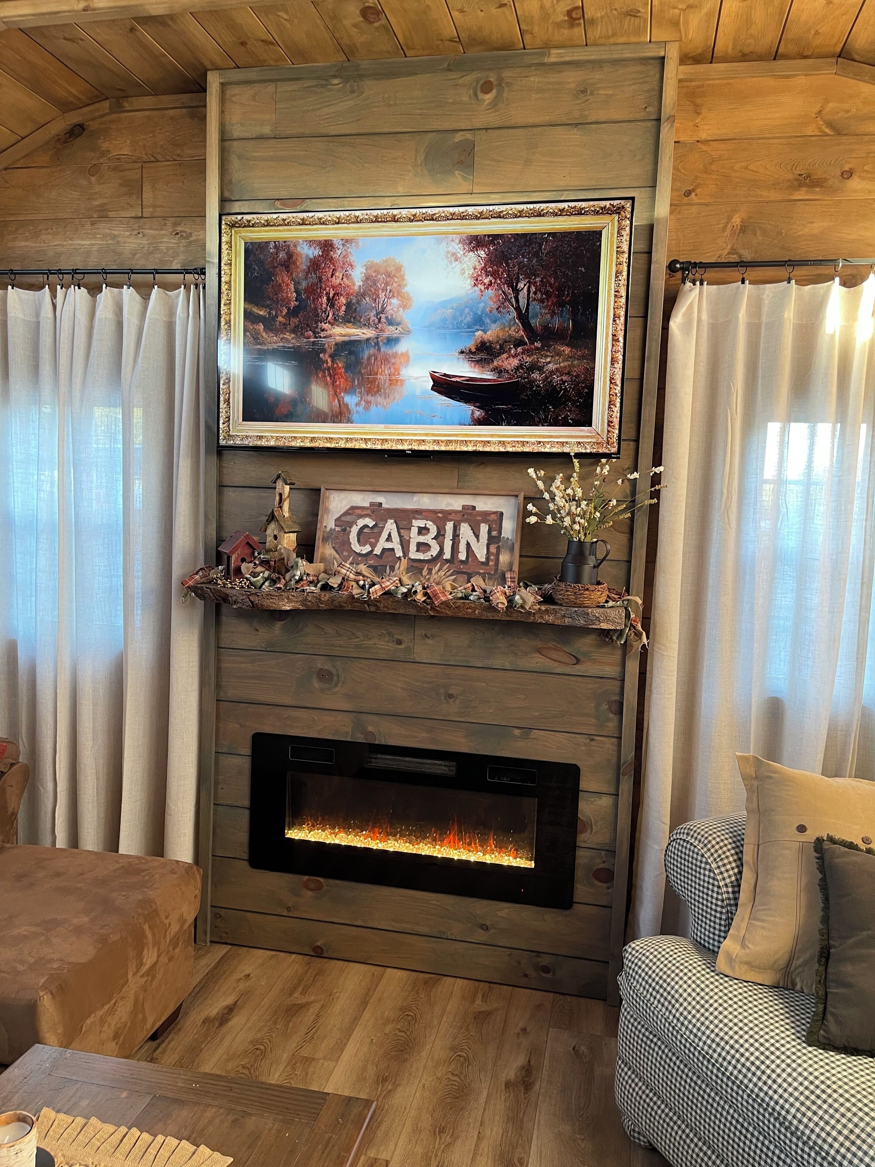 Un soggiorno in stile chalet con camino, televisore a parete e insegna decorativa.