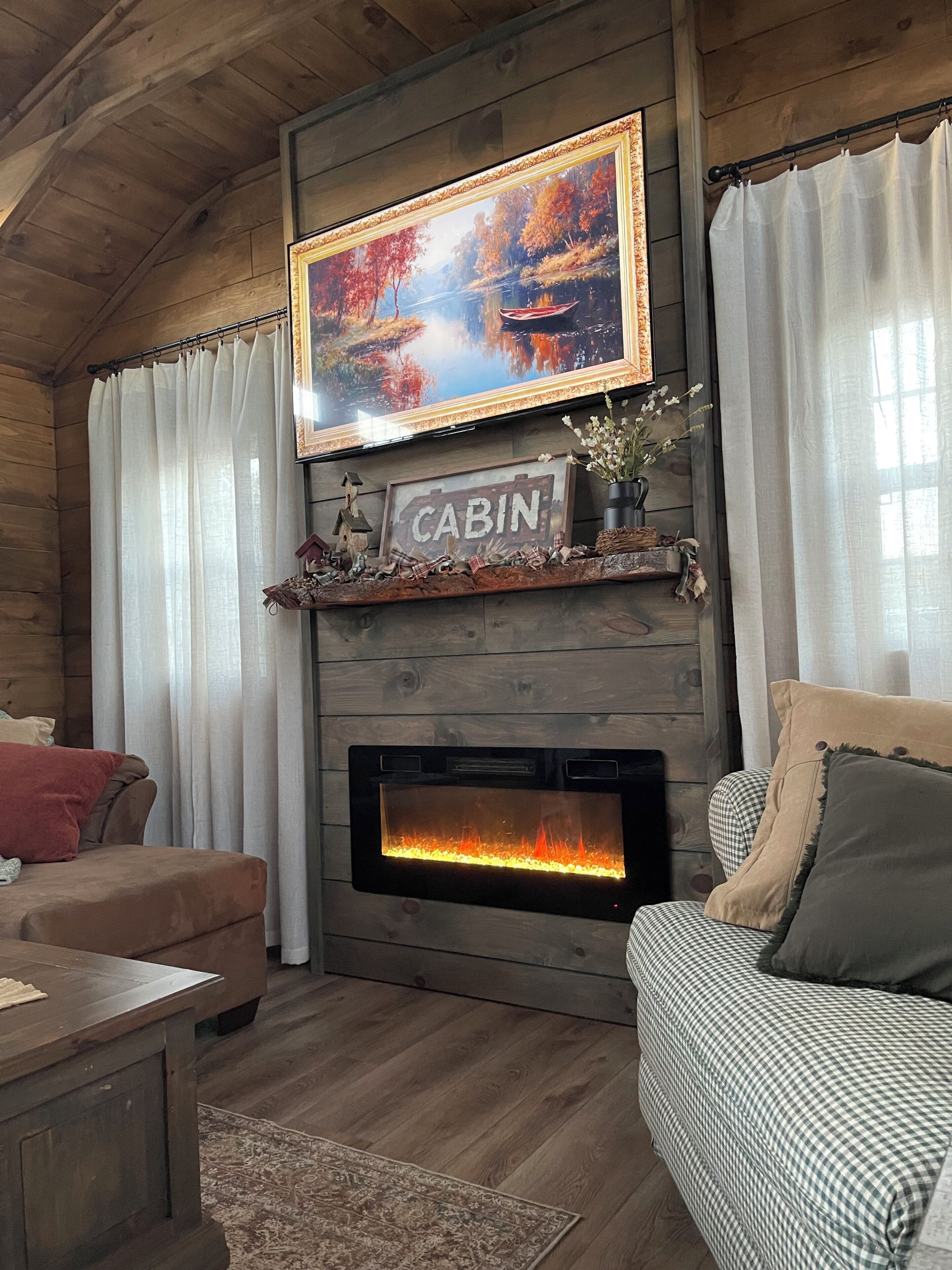 Una sala de estar con temática rústica, que incluye una chimenea, un televisor montado y un espacio de descanso acogedor.