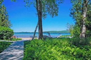 A pathway leading to a beach with a swing set and lush greenery. - After Dune Delight on Little Glen Lake (Empire)