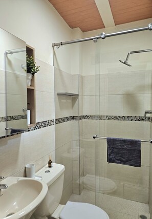A bathroom with a glass-enclosed shower, a sink, a toilet, and a mirror. - Wonderful 2-bedroom apartment in welcoming Cali neighborhood - 1 min San Antonio (Cali)