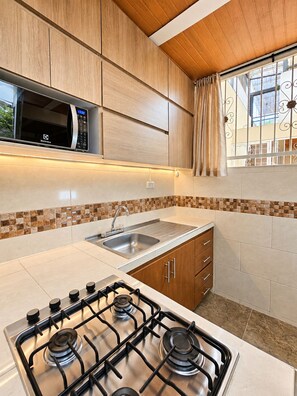 A modern kitchen with a gas stove, stainless steel sink, and wooden cabinets. - Wonderful 2-bedroom AC apartment in San Antonio - Cali (Cali)