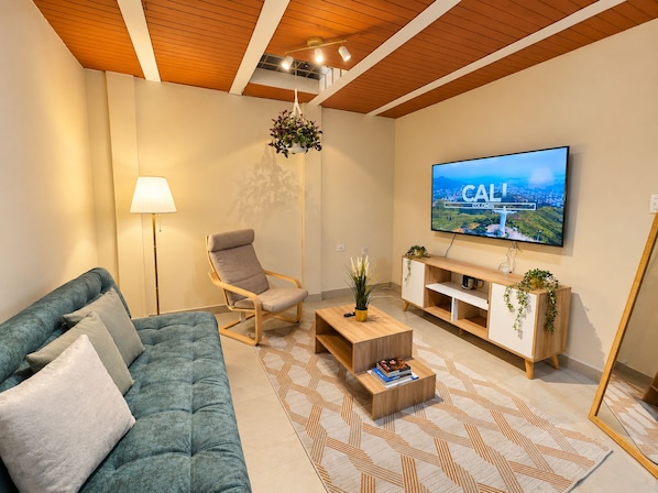 A modern living room with a sofa, armchair, coffee table, TV, and a plant. - Wonderful 2-bedroom AC apartment in San Antonio - Cali (Cali)