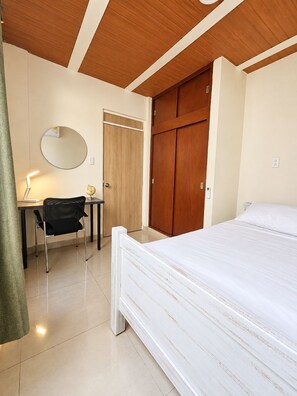 A bedroom with a bed, a desk with a chair, a wardrobe, and a mirror on the wall. - Wonderful 2-bedroom AC apartment in San Antonio - Cali (Cali)