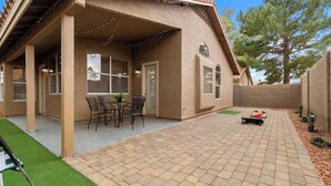 Ein überdachter Patio-Bereich mit Terrazzo-Boden, Sitzgelegenheiten im Freien und Lichterketten.