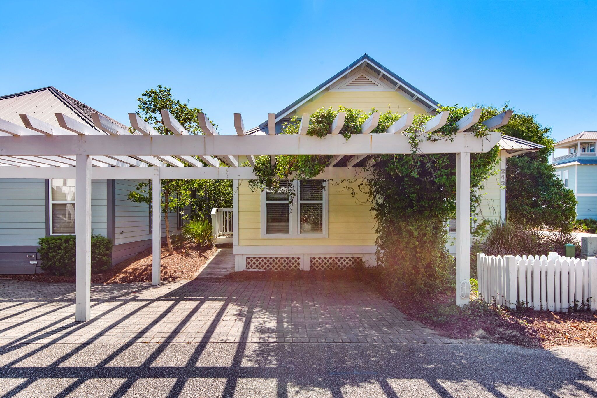 A house with a covered porch, a small front yard, and a white picket fence.