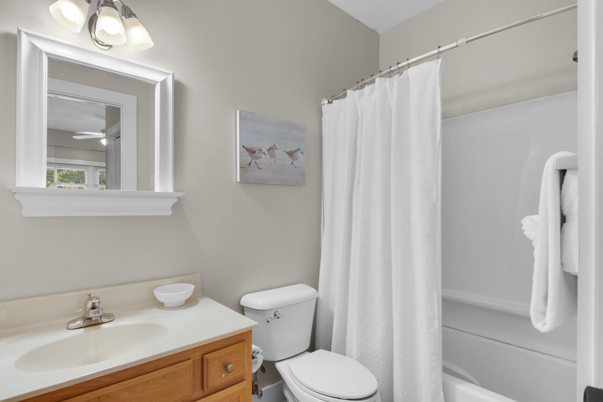 A bathroom with a sink, mirror, toilet, and shower curtain.