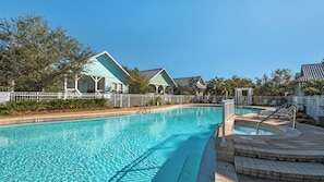 A clear swimming pool with a white fence, a covered seating area, and a building with a green roof. - Pet-friendly 3BR Cottage in Seacrest w/ Pool & Private Beach Access (Panama City Beach)