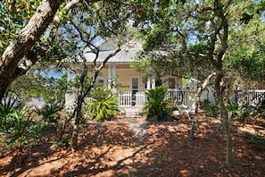 A house with a white porch, surrounded by trees and plants. - Pet-friendly 3BR Cottage in Seacrest w/ Pool & Private Beach Access (Panama City Beach)