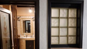 Un baño con piso de baldosas, un radiador blanco y una ventana con vidrio esmerilado.