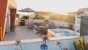 Een dakterras met een jacuzzi, tuinmeubels en een hangmat.