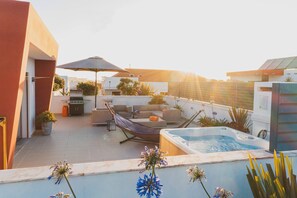 Eine Dachterrasse mit Whirlpool, Gartenmöbeln und einer Hängematte.